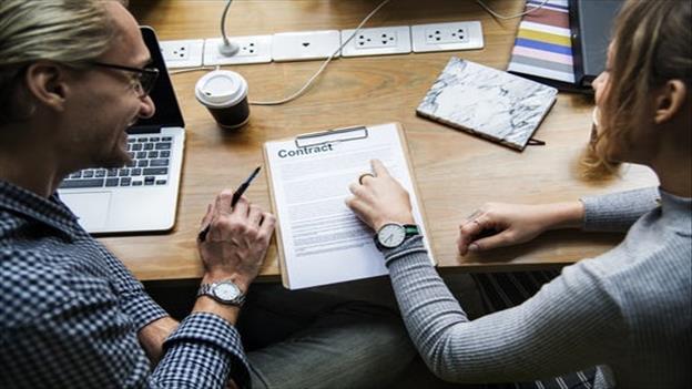 woman pointing out on contract form with man beside her smiling